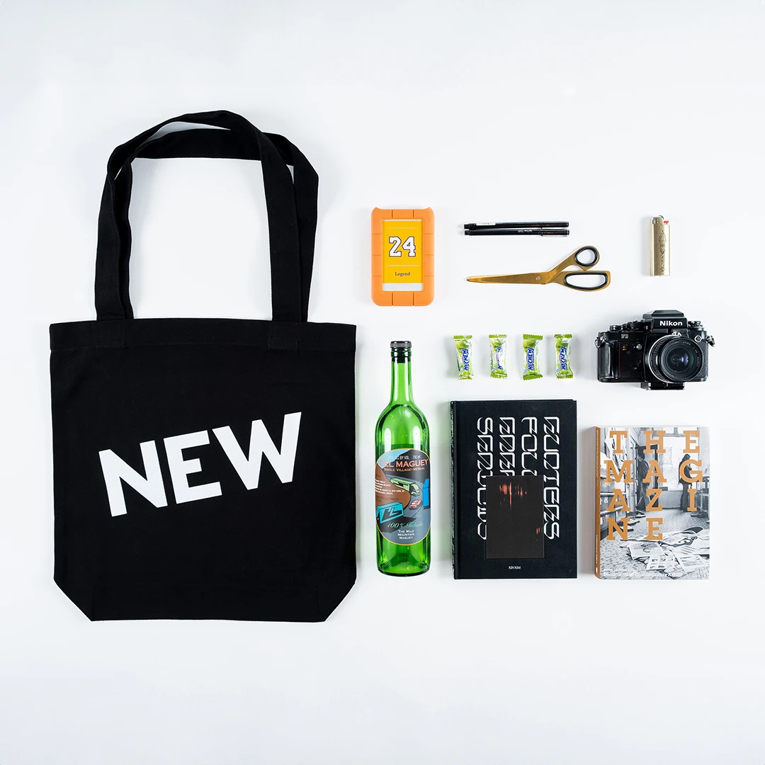 A knolling view of arranged items including a tote bag with the NEW logotype